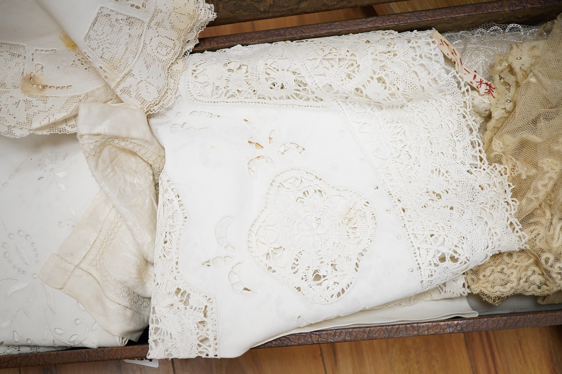A small box/trunk containing mixed crochet, embroidered anglaise and drawn thread table linens, christening gown, damask cloths and various pieces of lace etc.Ornate circular cloth 112cm diameter. Condition - most need r
